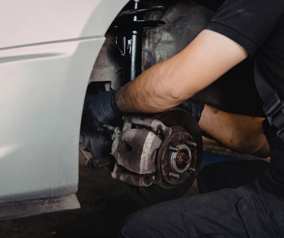 Mechanic Working On A Car's Disc Brake And Suspension Assembly