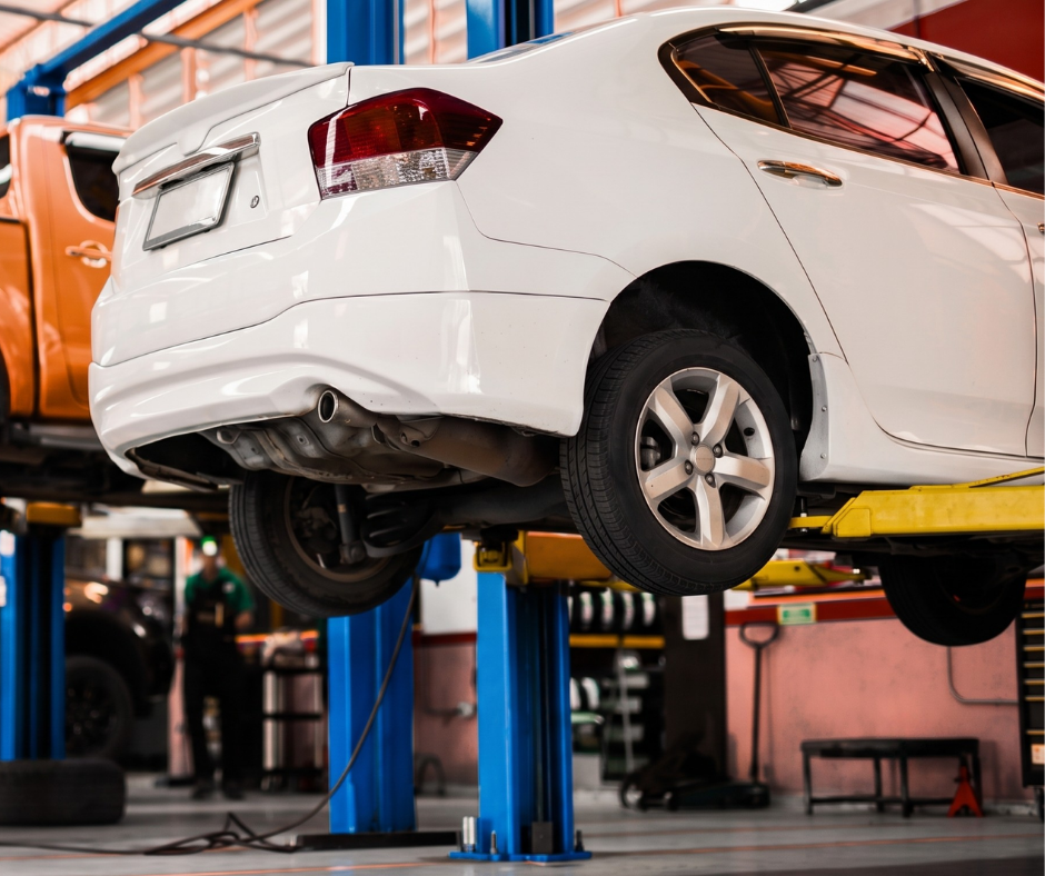 White Honda City Sedan Raised On A Hydraulic Two-Post Automotive Lift